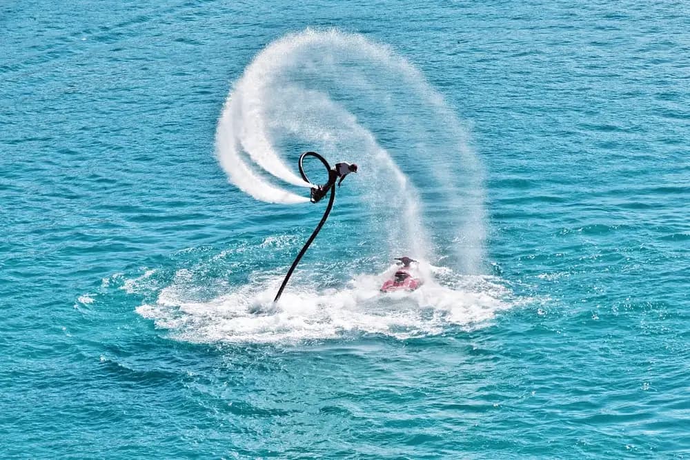 Person flyboarding above the water with a dramatic spray of water below them in Dubai