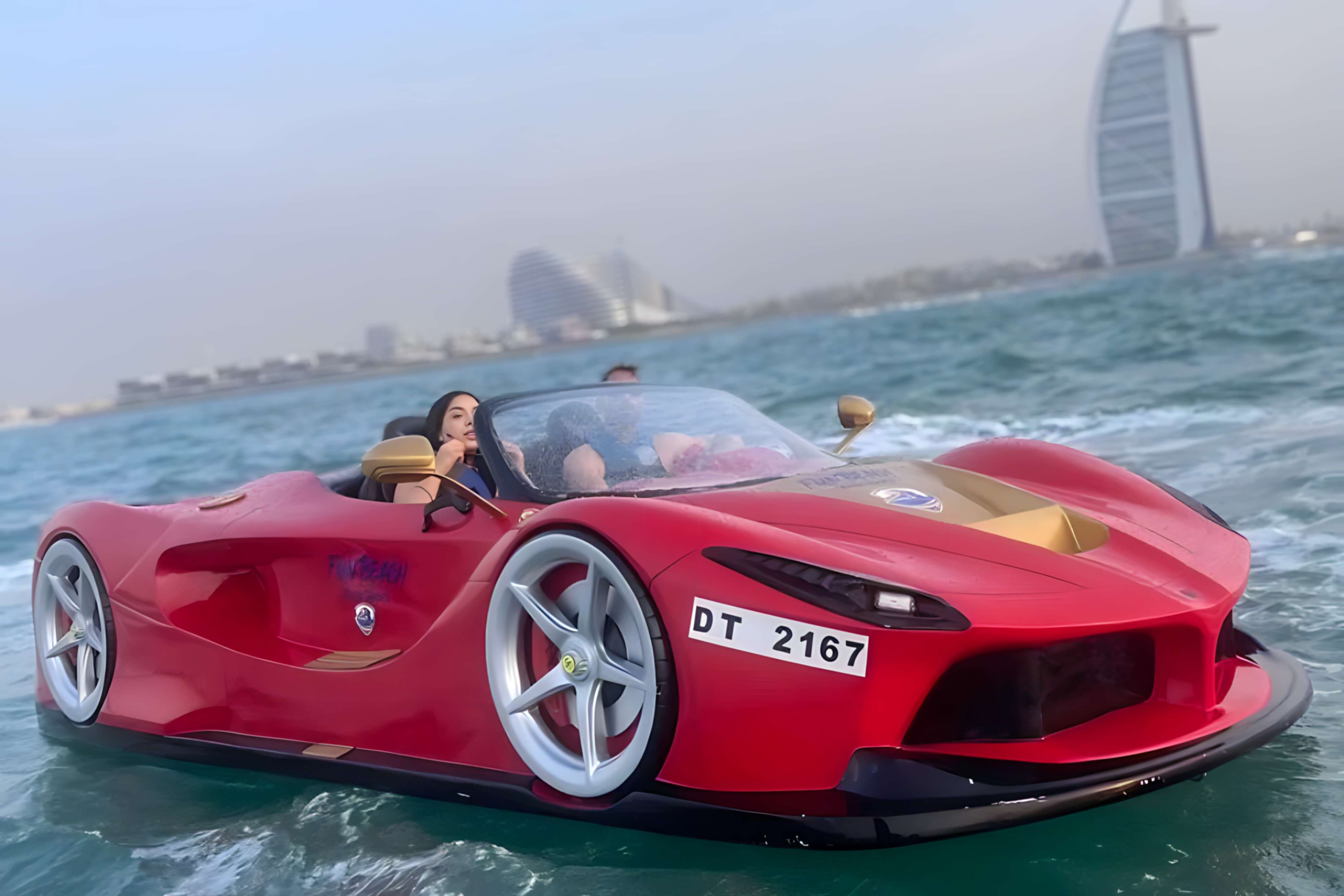 Couple driving a red luxury jet car on the water with the Burj Al Arab behind them in Dubai