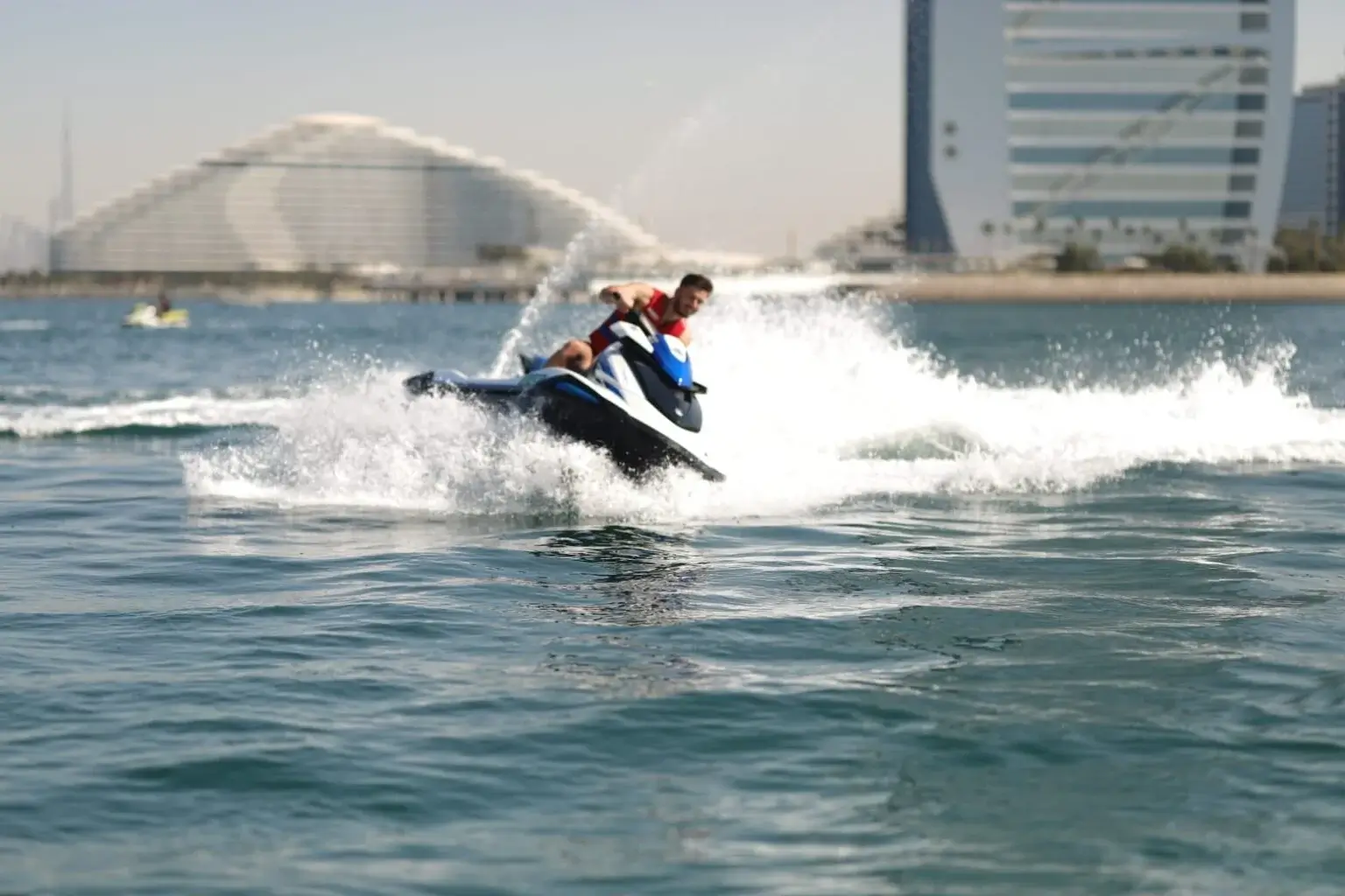 Jet ski rider leaning into a turn directly in front of the Burj Al Arab in Dubai